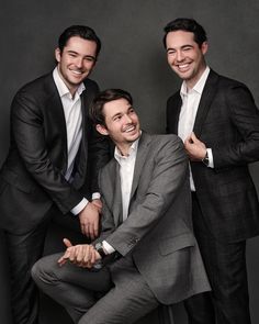 three men in suits are posing for the camera