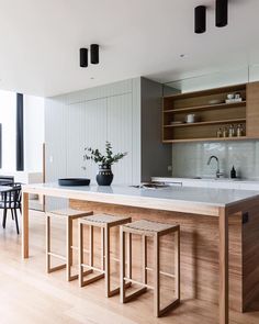 a kitchen with an island and stools next to it in front of a dining room table