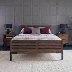 a wooden bed frame with purple pillows on it and two nightstands in the background