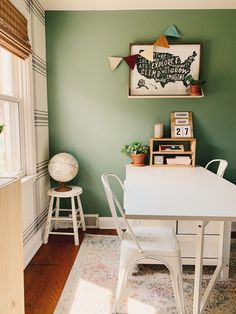 a dining room with green walls and white chairs