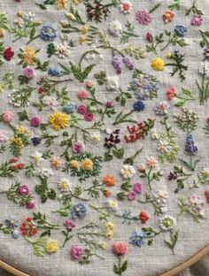 a close up of a embroidery on a piece of cloth with flowers in the middle