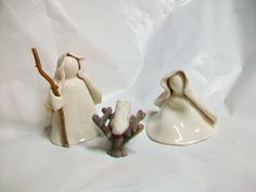 two white ceramic figurines sitting next to each other on a white sheeted surface