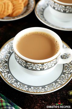 there is a cup of coffee on the saucer and two plates with cookies in the background