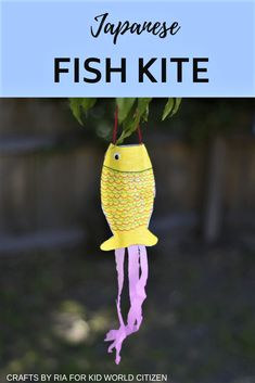 a yellow fish kite hanging from a tree with the words japanese fish kite on it