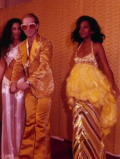 two women and a man dressed in disco outfits