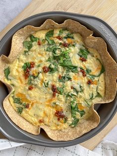 an omelet with spinach and cheese in a pan on a wooden table