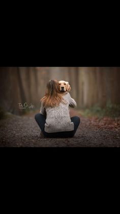 a woman sitting in the middle of a forest with her dog on her head,