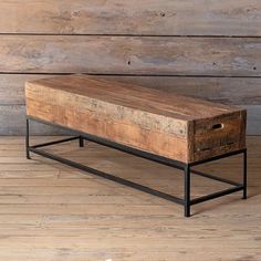 an old wooden table with metal legs and a drawer on the bottom, against a wood wall