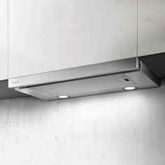 a stainless steel range hood mounted on the side of a white wall with two recessed lights