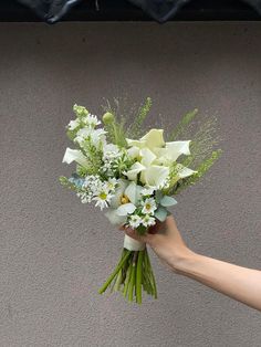 a person holding a bouquet of flowers in their hand on the side of a building