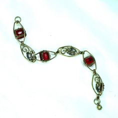 This is part of Chairish’s Costume Jewelry assortment.  1930s Art Deco 12k gold over sterling link bracelet. This delicate offering presents open elliptical links with smooth connectors, alternating heart-shaped leaves with emerald-cut ruby-colored  crystals. The workmanship is simple and meticulous, and the stones are vivid and evocative. Elegant and subtle, but with a hint of exuberance in the ruby crystals, this beauty is equally at home with a white shirt and jeans or a classic LBD. Not sign Heirloom Metal Bracelets For Formal Occasions, Heirloom Style Metal Bracelets For Formal Occasions, Vintage Yellow Gold Rectangular Link Jewelry, Vintage Yellow Gold Jewelry With Rectangular Links, Victorian Metal Bracelet Jewelry, Elegant Vintage Charm Oval Link Jewelry, Elegant Jewelry With Vintage Charm And Oval Link, Antique Ruby Jewelry With 17 Jewels, Victorian Metal Bracelet