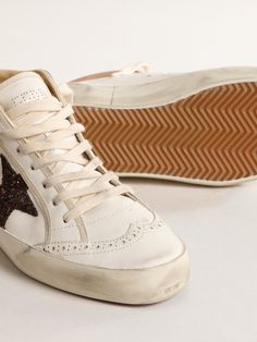 Uniquely elegant versatility: the Mid Star sneakers take a refined approach to their Nineties skate scene inspiration. This model with a white nappa leather upper with ecru cotton trim features a brown glitter star and a nude waxed leather flash. The silver metallic leather heel tab, beige suede insert on the back and ecru laces complete the look. Golden Family, Mid Top Sneakers, Golden Goose Deluxe Brand, Glitter Stars, Mid Top, Star Sneakers, Golden Goose, Metallic Leather, Nappa Leather