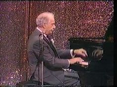 a man in a suit and tie playing a piano