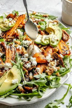 a salad with carrots, avocado, and feta cheese on it