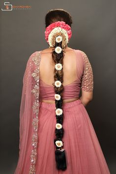 a woman in a pink dress with flowers on her head and long hair tied into a braid