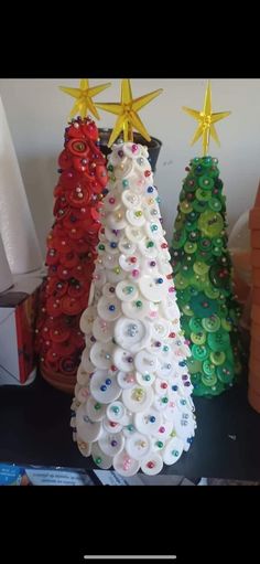 three christmas trees made out of buttons and plastic caps are sitting next to each other