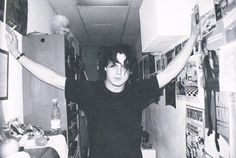 a young man is holding his hands up in the air while standing next to a refrigerator