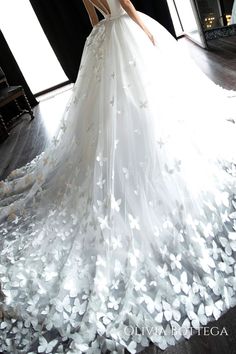 a woman in a white wedding dress with butterflies all over it's skirt and back