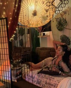 a woman laying on top of a bed next to a cage with an umbrella hanging from it