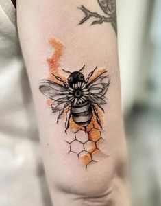 a tattoo on the arm of a woman with a bee and honeycombs painted on it