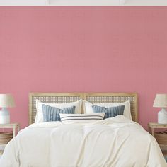 a bedroom with pink walls and white bedding, two lamps on either side of the bed