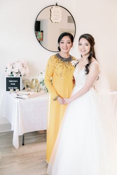 two women standing next to each other in front of a table with flowers on it