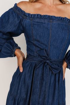 Embrace your cute cowgirl era in this western-inspired dress with a feminine touch Classic denim blue color Cotton material has no stretch Ruffled neckline Smocking at back Long off-shoulder sleeves with elastic at cuffs Removable self-tie waist sash Functional side pockets Tiered skirt Unlined 100% Cotton Skye is 5'9, cup size 32A, size 0 and wearing size S Cowgirl Era, Cocktail Jumpsuit, Cute Cowgirl, Destination Dress, Baltic Born, Waist Sash, Dress Denim, Ruffled Neckline, Romper Outfit