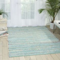 a living room area with a rug and potted plants