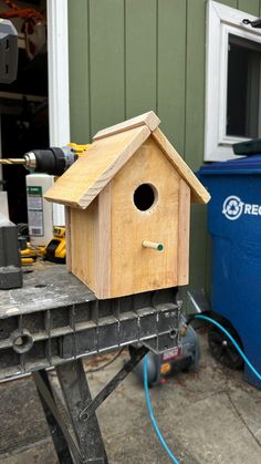 a wooden birdhouse sitting on top of a work bench