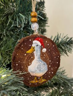 a wooden ornament with a duck on it hanging from a christmas tree branch