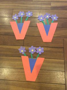 paper flowers are placed in the shape of letters v and v on a wooden floor