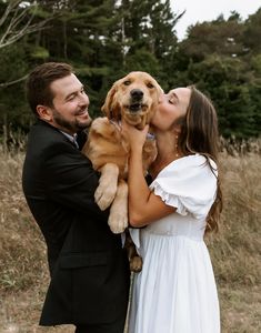 a man and woman kissing while holding a puppy