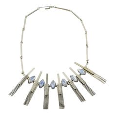 This stunning 1970s Space Age choker necklace has a modernist geometric central pendant. The necklace boasts a rigid chrome-plated metal chain adorned with a large central pendant and has a hook-closing clasp. The geometric is topped with oval opal-like blue glass cabochons. There is no visible maker's mark. The necklace is in good condition, with minor fading on the metal edges. Measurements: The necklace's total length is 17.75 in (45 cm) - The pendant is 2.25 in high (5.7 cm) x 6.32 in wide ( Vintage Choker Necklace, Vintage Choker, Antique Pendant, Chrome Metal, Heart Pendant Diamond, Geometric Pendant, Maker's Mark, Space Age, Blue Opal