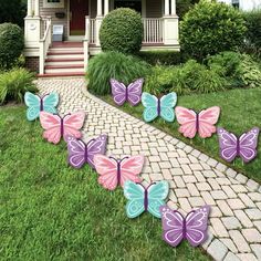 some purple and blue butterflies are in front of a house on the grass with bushes