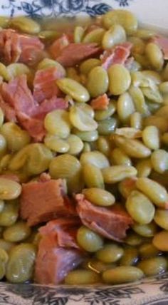 a bowl filled with green beans and ham on top of a blue and white plate