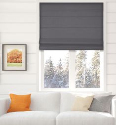 a white couch sitting under a window in a living room next to two pictures on the wall