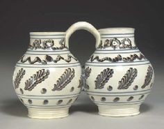 two white vases with designs on them sitting next to each other in front of a gray background