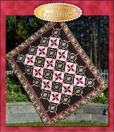 a black and pink quilt on display in front of a brick wall with an award seal