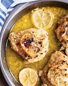 two pieces of chicken in a pan with lemons