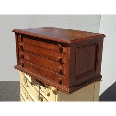 an old wooden chest of drawers sitting on top of a table next to a wall