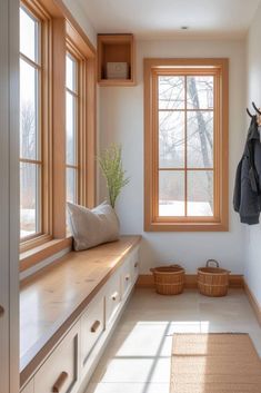 a coat rack in the corner of a room next to a window with two large windows