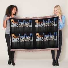 two women holding up a basketball blanket with the words basketball written on it in front of them