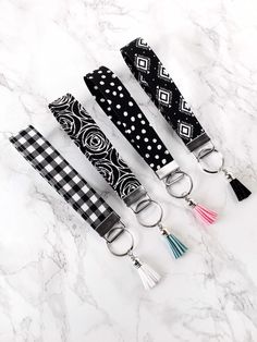 four black and white keychains with tassels on them sitting on a marble surface