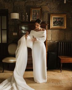 a woman in a white dress is posing for the camera with her arms wrapped around her body