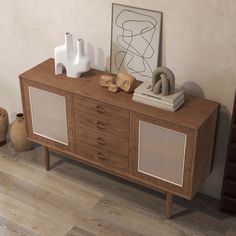 a wooden sideboard with two speakers on top and some vases next to it