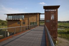 a wooden building with a metal fence around it's sides and a walkway leading to the upper level