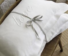 two white pillows tied to each other with the word love written on them in cursive font