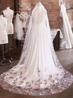 a wedding dress on display in front of mannequins and other bridal gowns