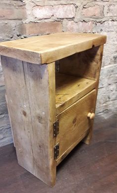 an old wooden cabinet sitting on top of a hard wood floor next to a brick wall