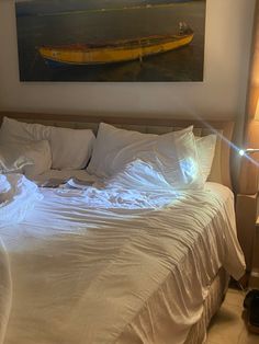 a bed with white linens and a yellow boat on the wall above it in a bedroom